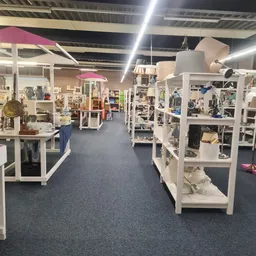 Winkelvloer met stellingen vol huishoudelijke spullen, verlichting, en diverse tweedehandsartikelen