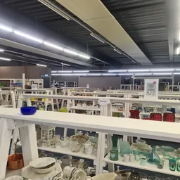 Winkelvloer met witte stellingen en rekken vol huishoudartikelen en decoratieve spullen onder LED-verlichting