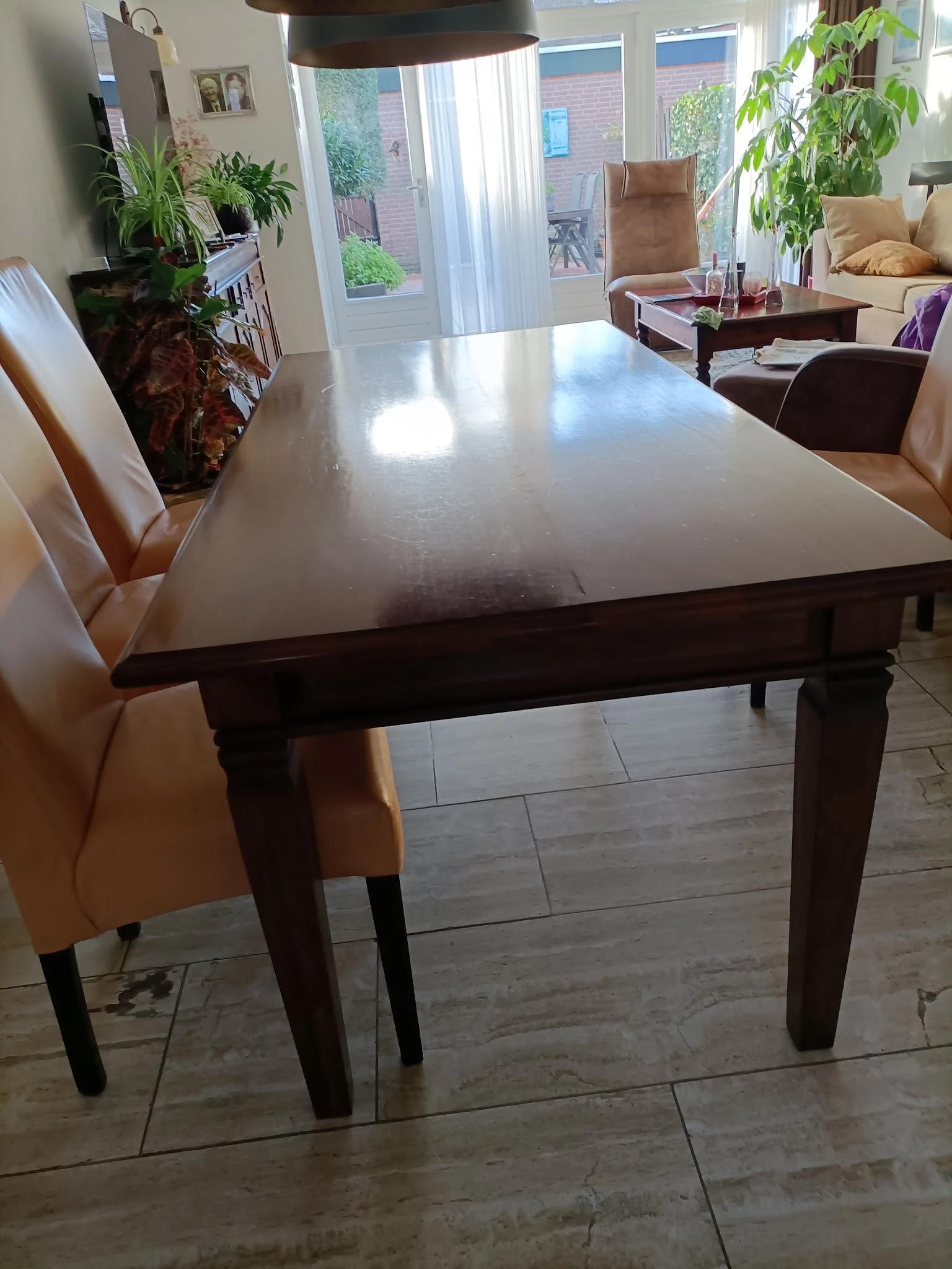 Glanzende grijze eettafel met donkerbruine houten poten en beige stoelen ernaast