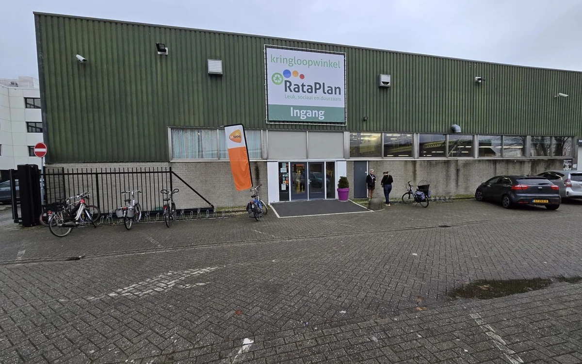 Voorkant van kringloopwinkel RataPlan met groene golfplaten gevel, ingang met glazen deuren en fietsen geparkeerd ervoor