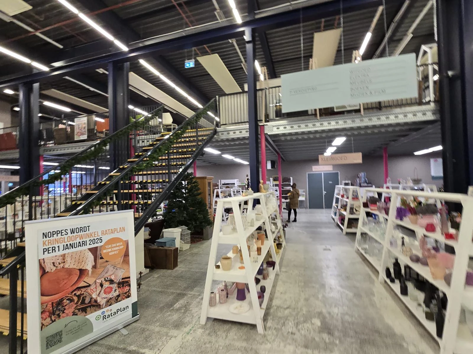 Spacieus winkelinterieur met witte stellingen, trappen en industriële plafondverlichting