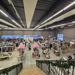 Ruim kringloopwinkels interieur met kledingrekken onder roze parasols en led-verlichting