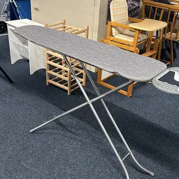 Strijkplank met grijze strijkplanksnoes op metalen statief in winkelpand