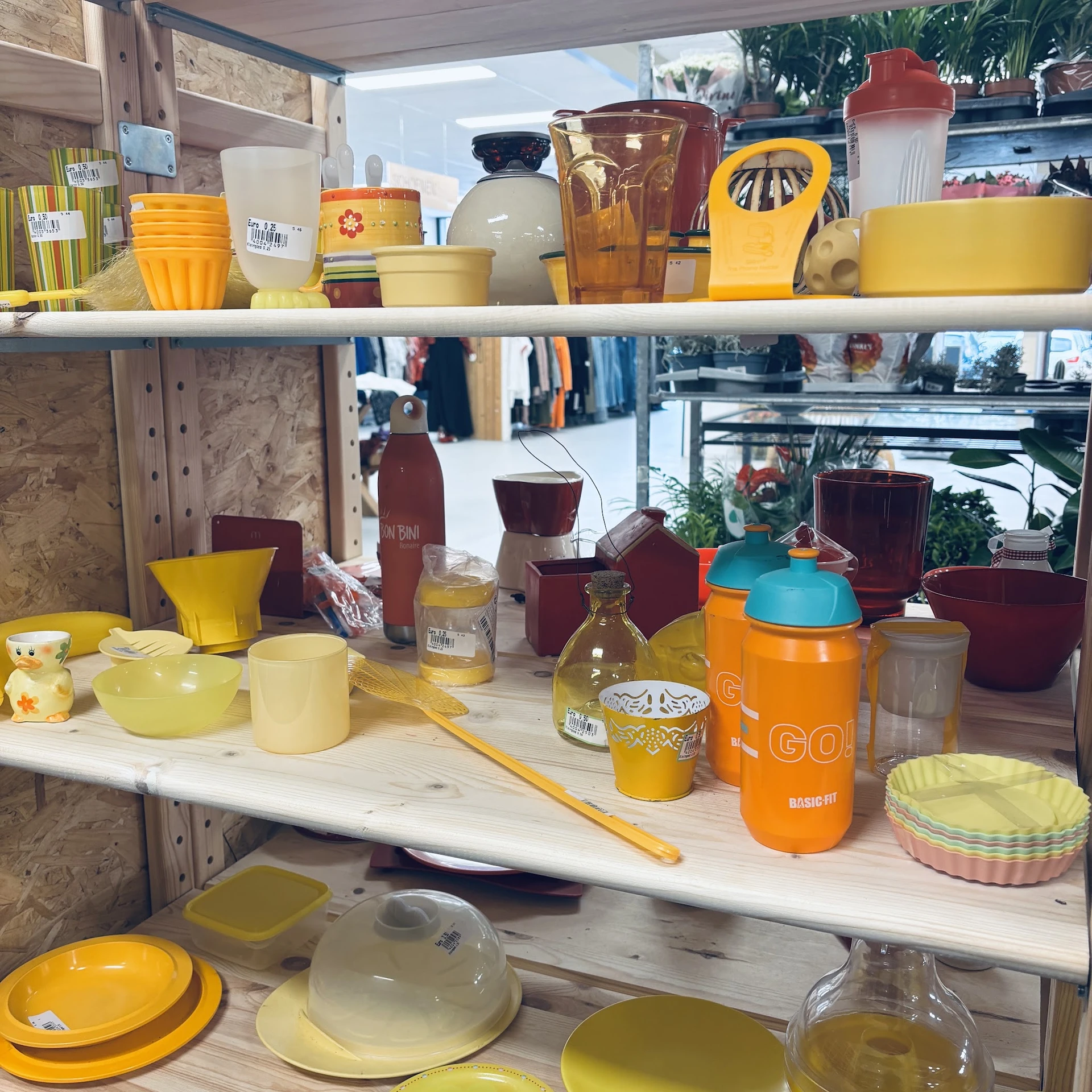 Stellingen met geel en bordeauxrood huishoudelijke artikelen: schalen, potjes, pannen en keukengerei
