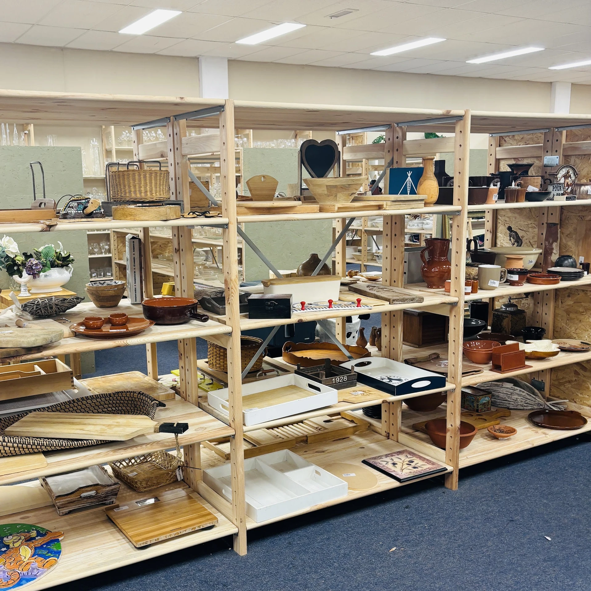 Houten stellingen vol met tweedehands huishoudartikelen, servies, decoratie en diverse voorwerpen in een kringloopwinkel