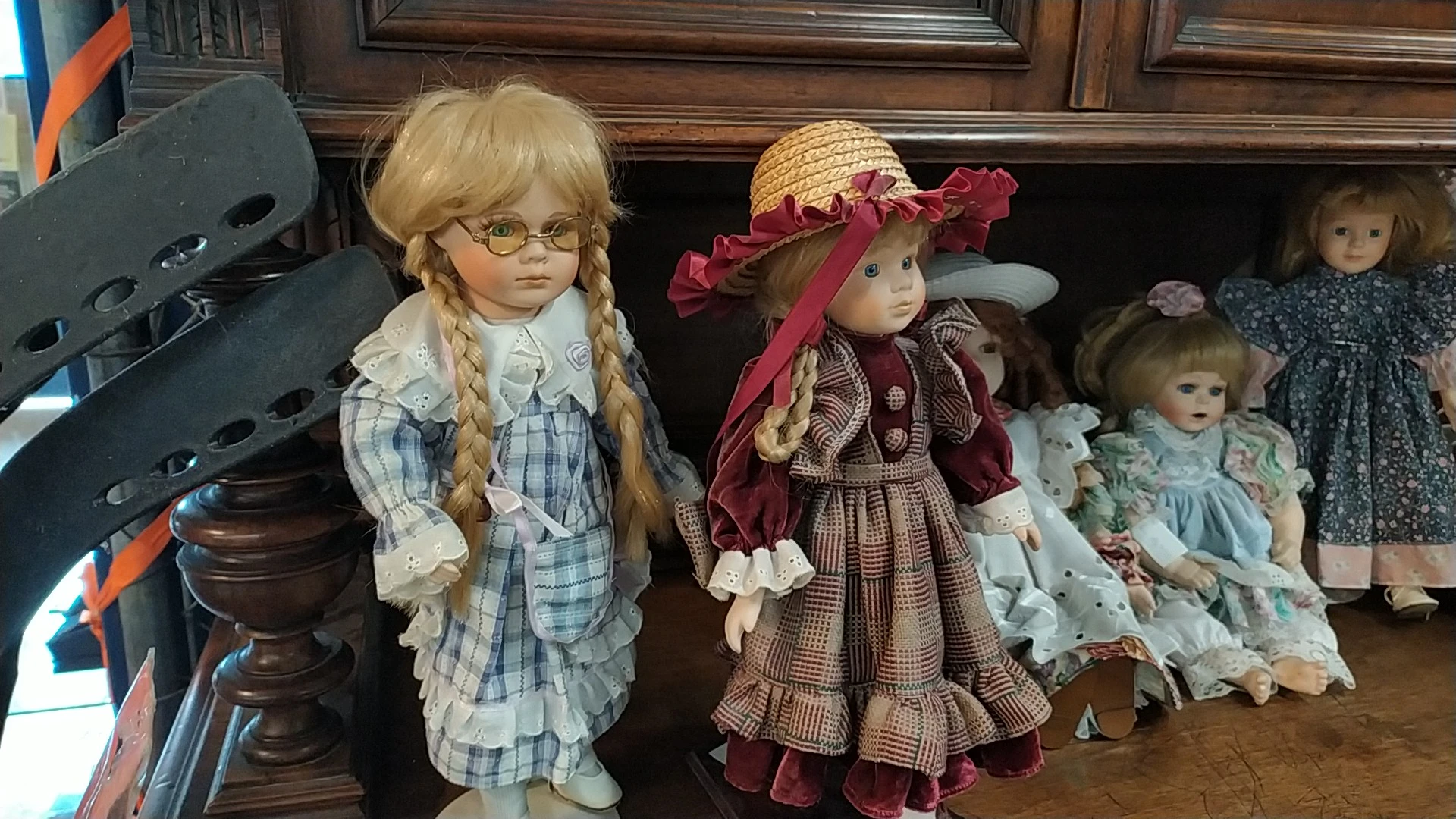 Vier porseleinpoppen met vintage kleding en accessoires in een houten kast