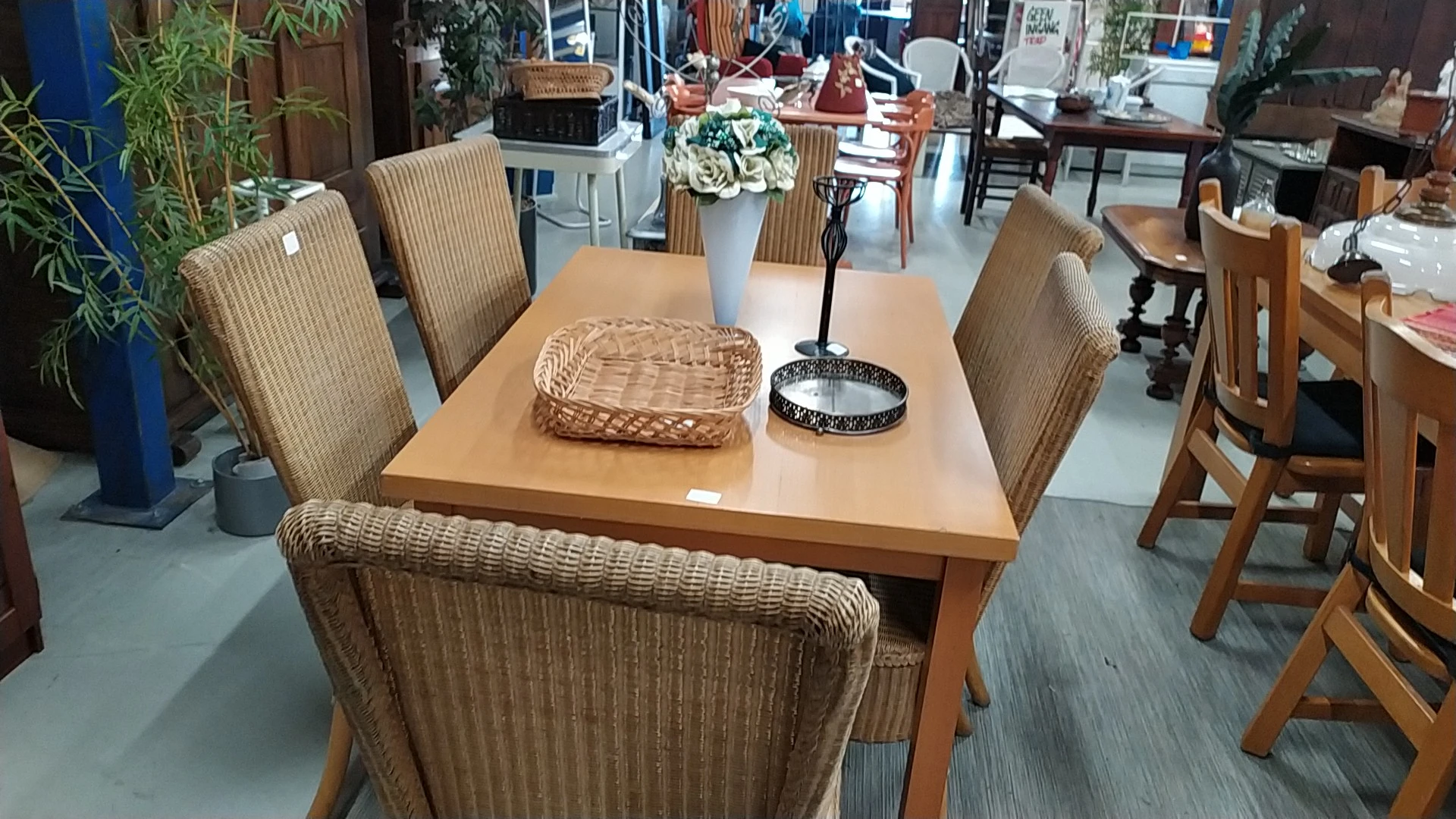 Houten eettafel met rieten stoelen en diverse decoratieve items zoals manden en bloemen