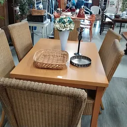 Houten eettafel met rieten stoelen en diverse decoratieve items zoals manden en bloemen
