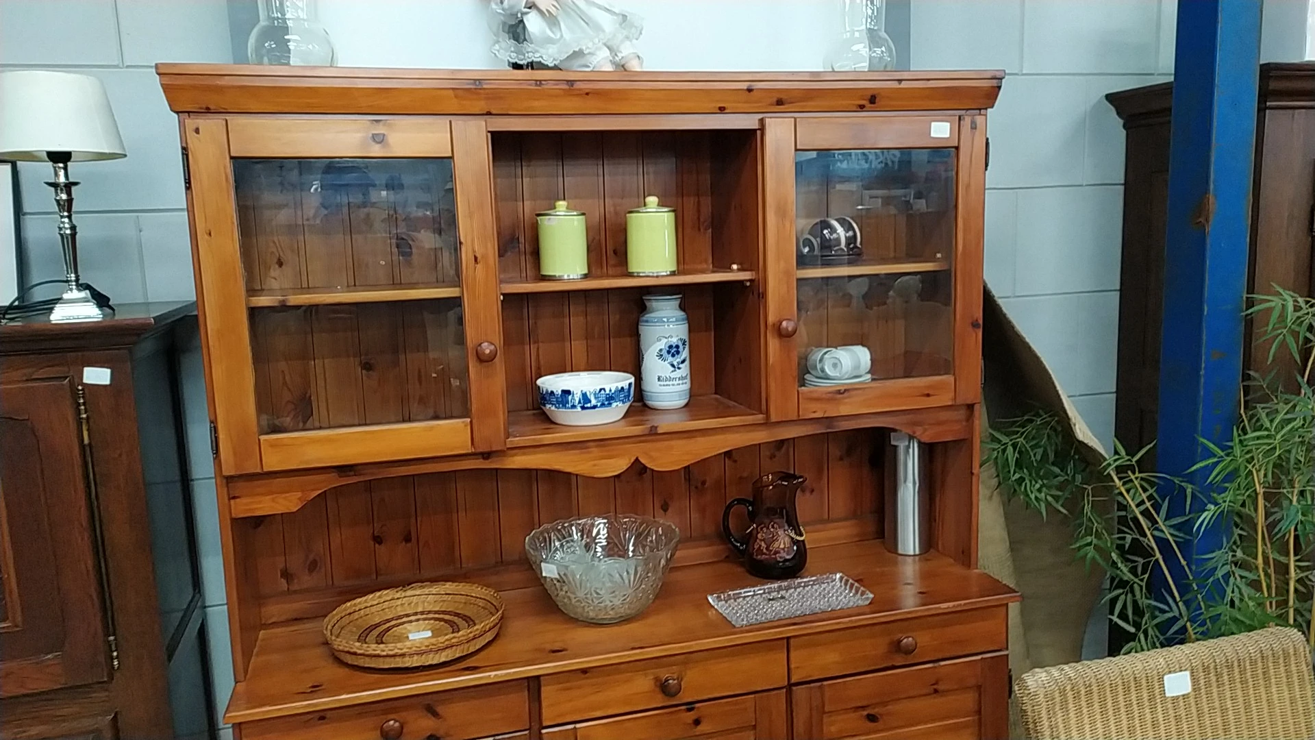 Houten vitrinekast met gesloten kastjes en glazen deuren, gevuld met decoratieve objecten en serviesgoed