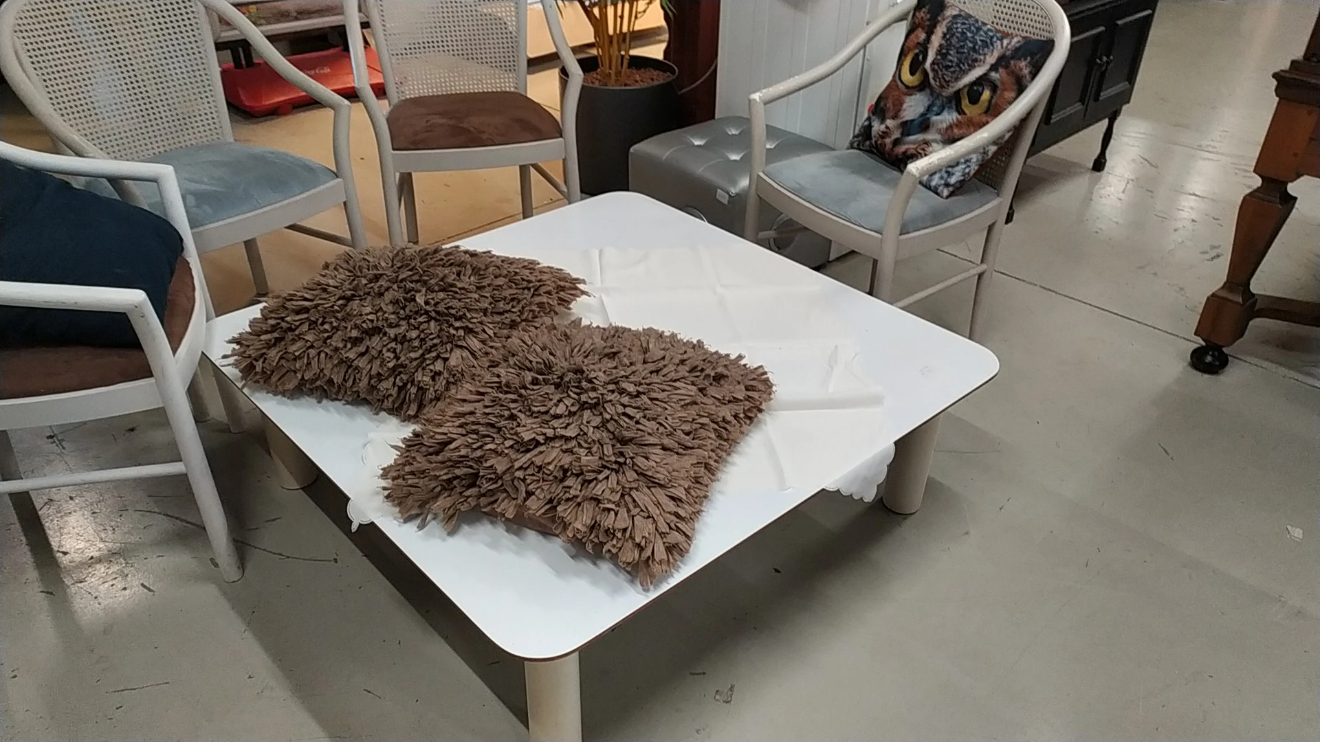 Twee bruine pluche kussens op een witte tafel in de winkel, omgeven door stoelen