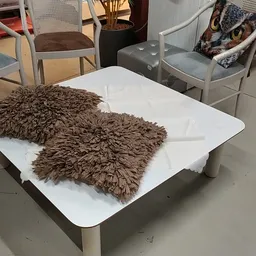 Twee bruine pluche kussens op een witte tafel in de winkel, omgeven door stoelen