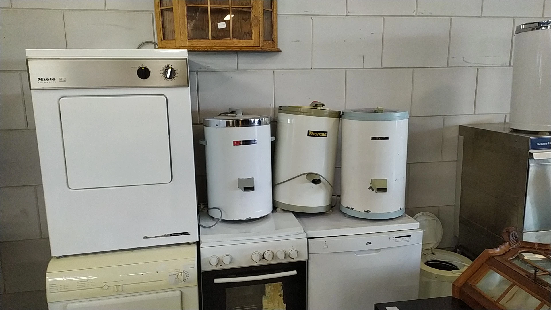 Drie witte boilers en huishoudelijke apparaten tegen de muur in de winkel