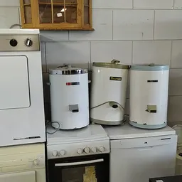 Drie witte boilers en huishoudelijke apparaten tegen de muur in de winkel