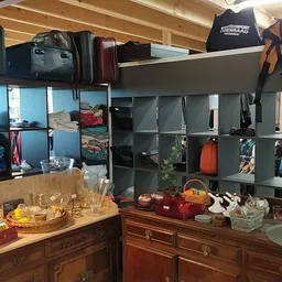 Kringloopwinkelinterieur met stellingen vol tweedehands spullen, houten kasten met servies en decoraties