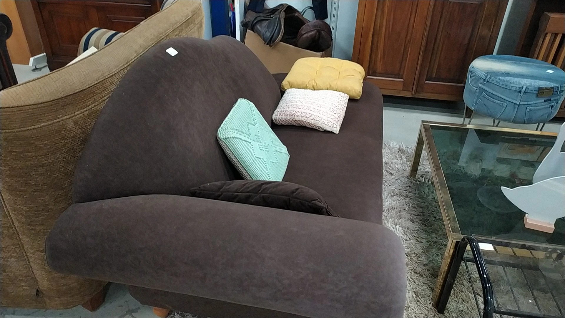 Bruine fauteuil met gekleurde kussens in de winkel