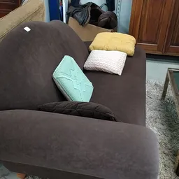 Bruine fauteuil met gekleurde kussens in de winkel