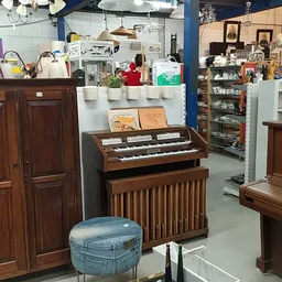 Winkelvloer met houten meubels, een elektronisch orgel, kasten en diverse spullen op stellingen