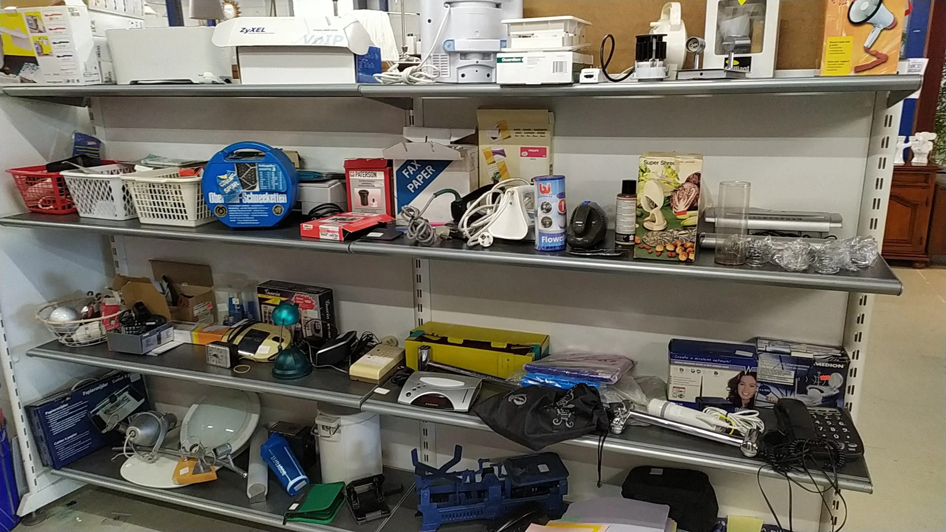 Stellingen met diverse tweedehands elektronica, apparaten en huishoudelijke artikelen