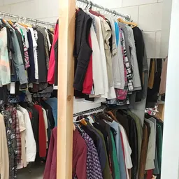 Houten stellingen met uitgestalde tweedehands kleding in verschillende kleuren en stijlen