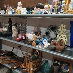 Planken met diverse tweedehands decoratieartikelen, beeldjes, vazen, kandelaren en huishoudspullen