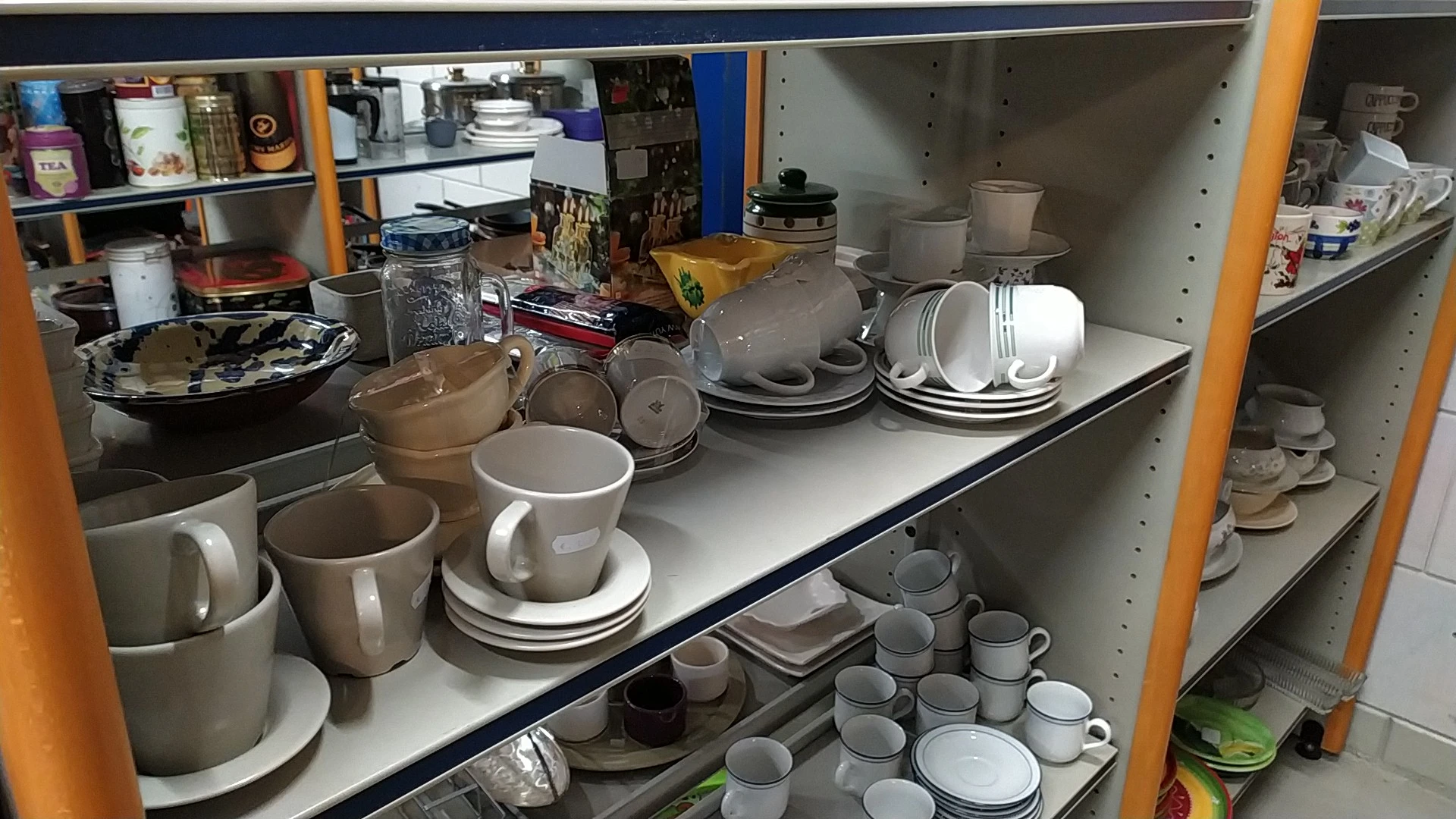 Stellingen met servies, kopjes, schotels en ander keramiekgoed in de kringloopwinkel
