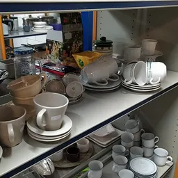 Stellingen met servies, kopjes, schotels en ander keramiekgoed in de kringloopwinkel