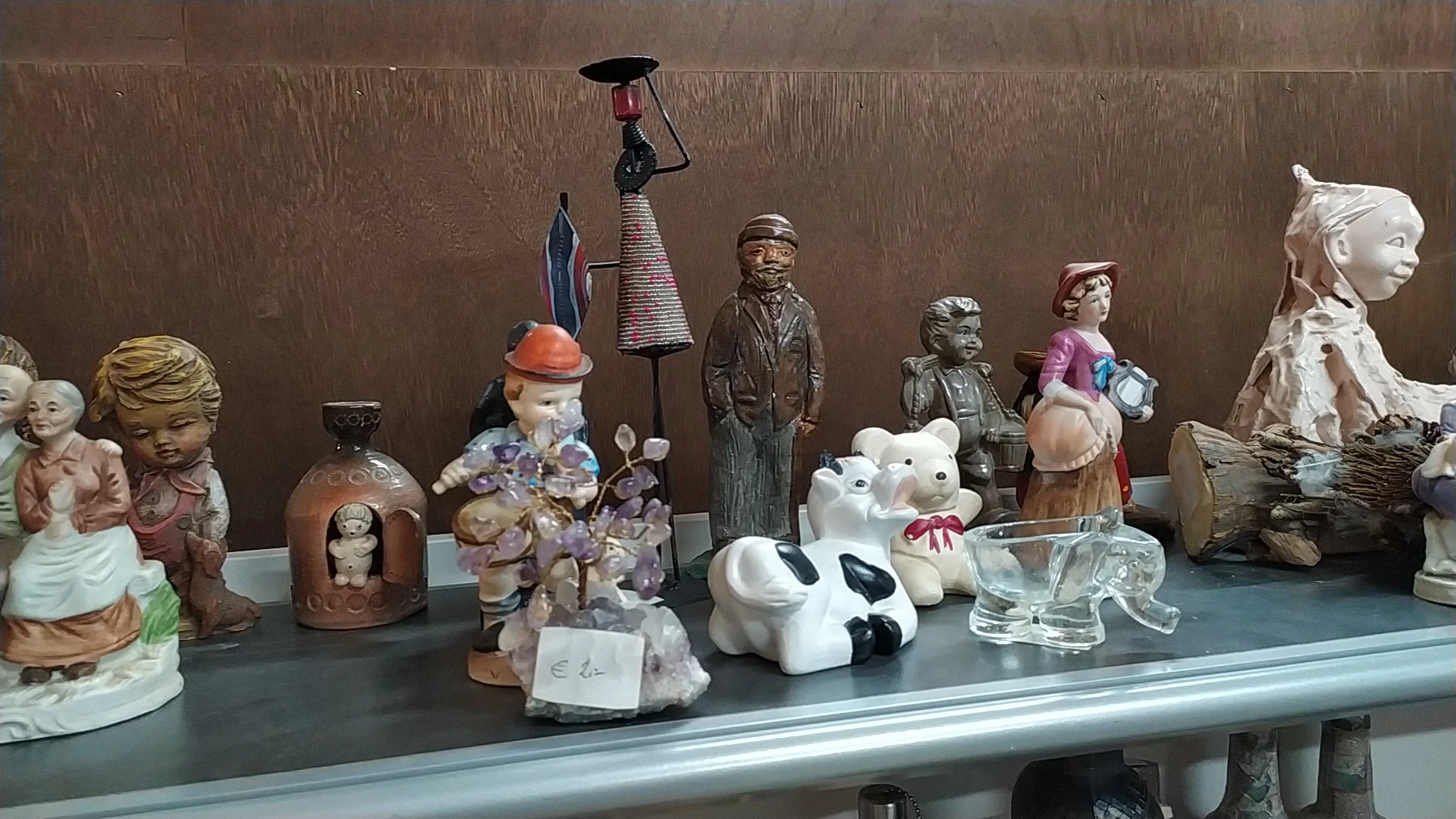 Verzameling tweedehands decoratieartikelen en beeldjes op een tafel: porseleinpoppen, keramische dieren, vintage figuren en o
