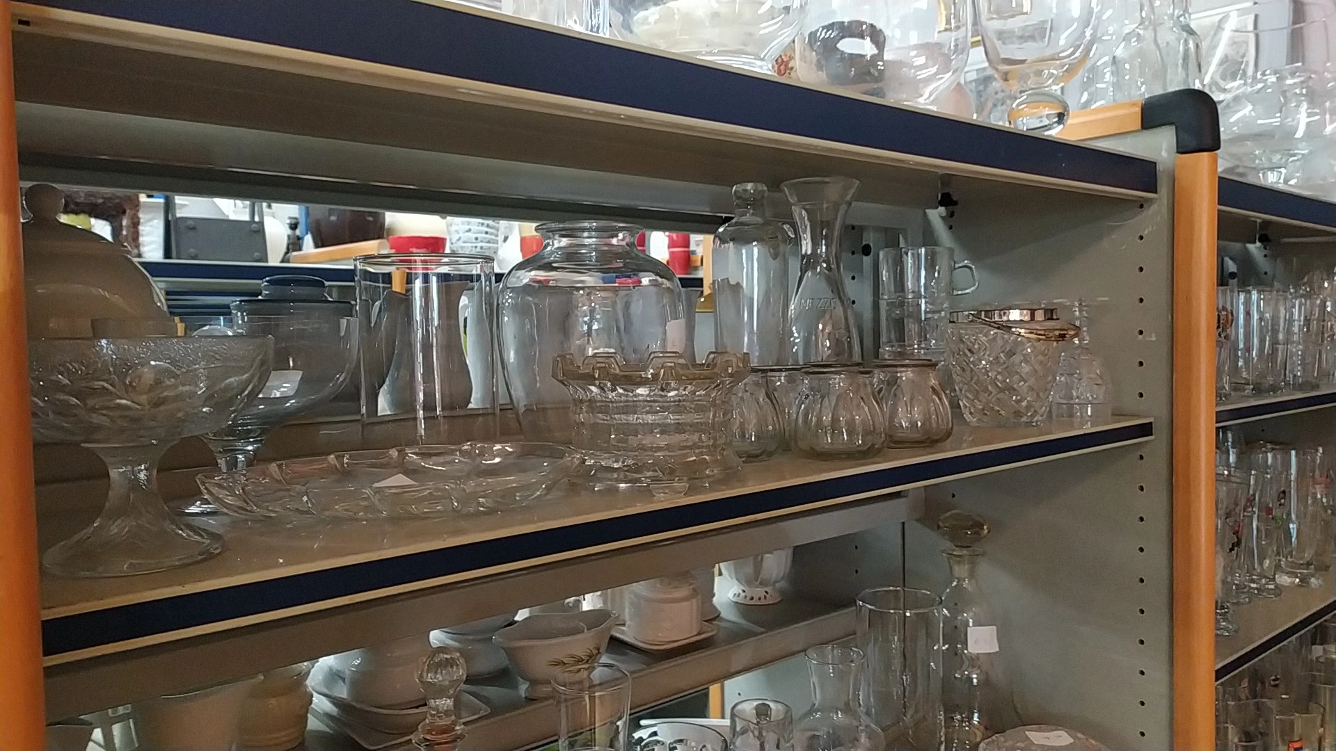 Stellingen met glazen serviesgoed, potten en drinkglazen in verschillende maten en vormen