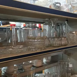 Stellingen met glazen serviesgoed, potten en drinkglazen in verschillende maten en vormen