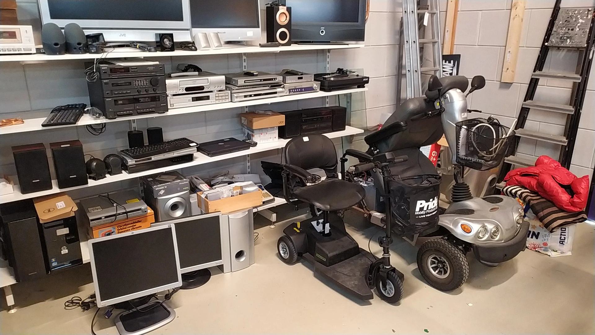 Stellingen met elektronica, monitors, versterkers en twee elektrische scooters in de winkel