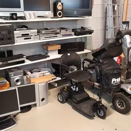 Stellingen met elektronica, monitors, versterkers en twee elektrische scooters in de winkel