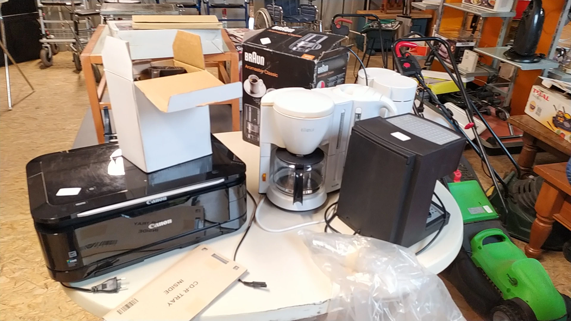 Verzameling tweedehands elektrische huishoudapparatuur: koffiezetapparaat, printer en andere elektronische apparaten op werkb
