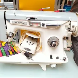 Witte Baronie naaimachine van dichtbij met gekleurde stoffen ernaast