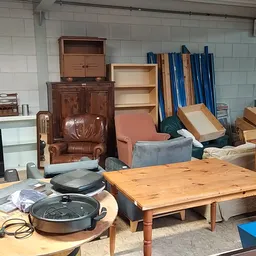 Tweedehands meubels in een kringloopwinkel: tafels, kasten, stoelen en huishoudapparatuur.