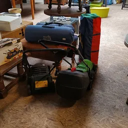 Winkelvloer met diverse tweedehands spullen en meubels, waaronder een grill, opbergkisten en huishoudartikelen.