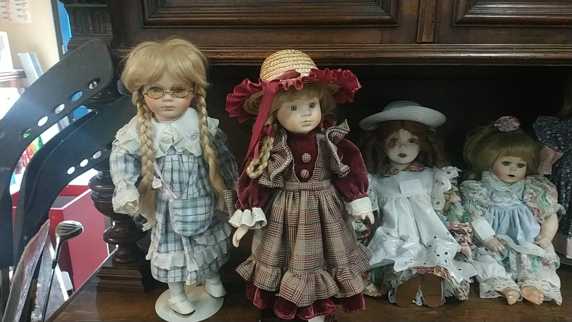 Vier porseleinpoppen met verschillende outfits en hoeden op een schap