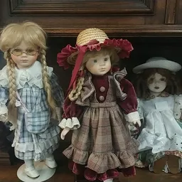 Vier porseleinpoppen met verschillende outfits en hoeden op een schap