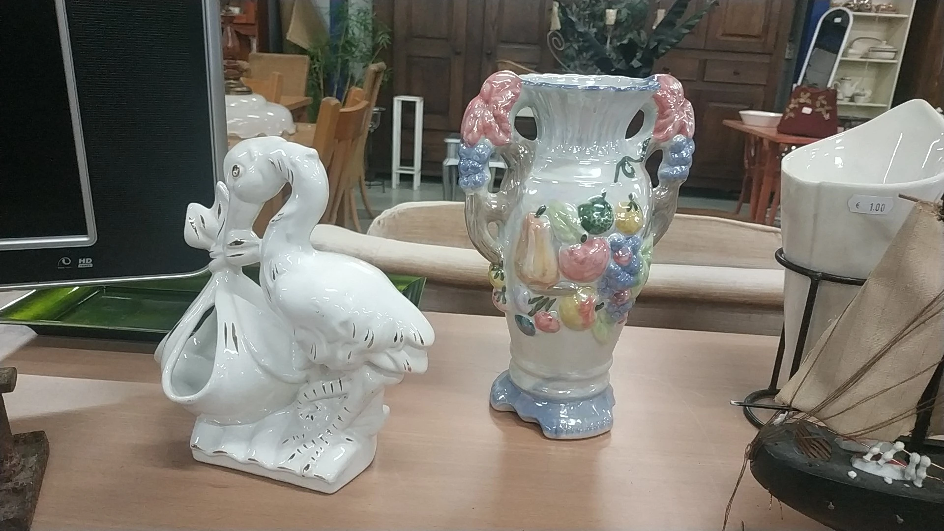 Twee decoratieve vazen op een tafel: een witte zwaan en een grijze vaas met bloemenopdruk