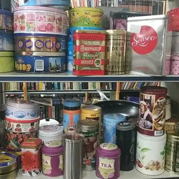 Twee schappen vol met diverse blikken, tins en dozen, waaronder thee, koffie en andere voorraden