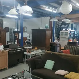 Winkelvloer met meubels, kunstobjecten en huishoudartikelen onder industriële verlichting