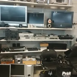 Stellingen met tweedehands elektronica zoals monitors, printers en andere apparaten