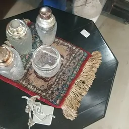 Glazen potten en potjes op een decoratief kleedje op een zwarte tafel