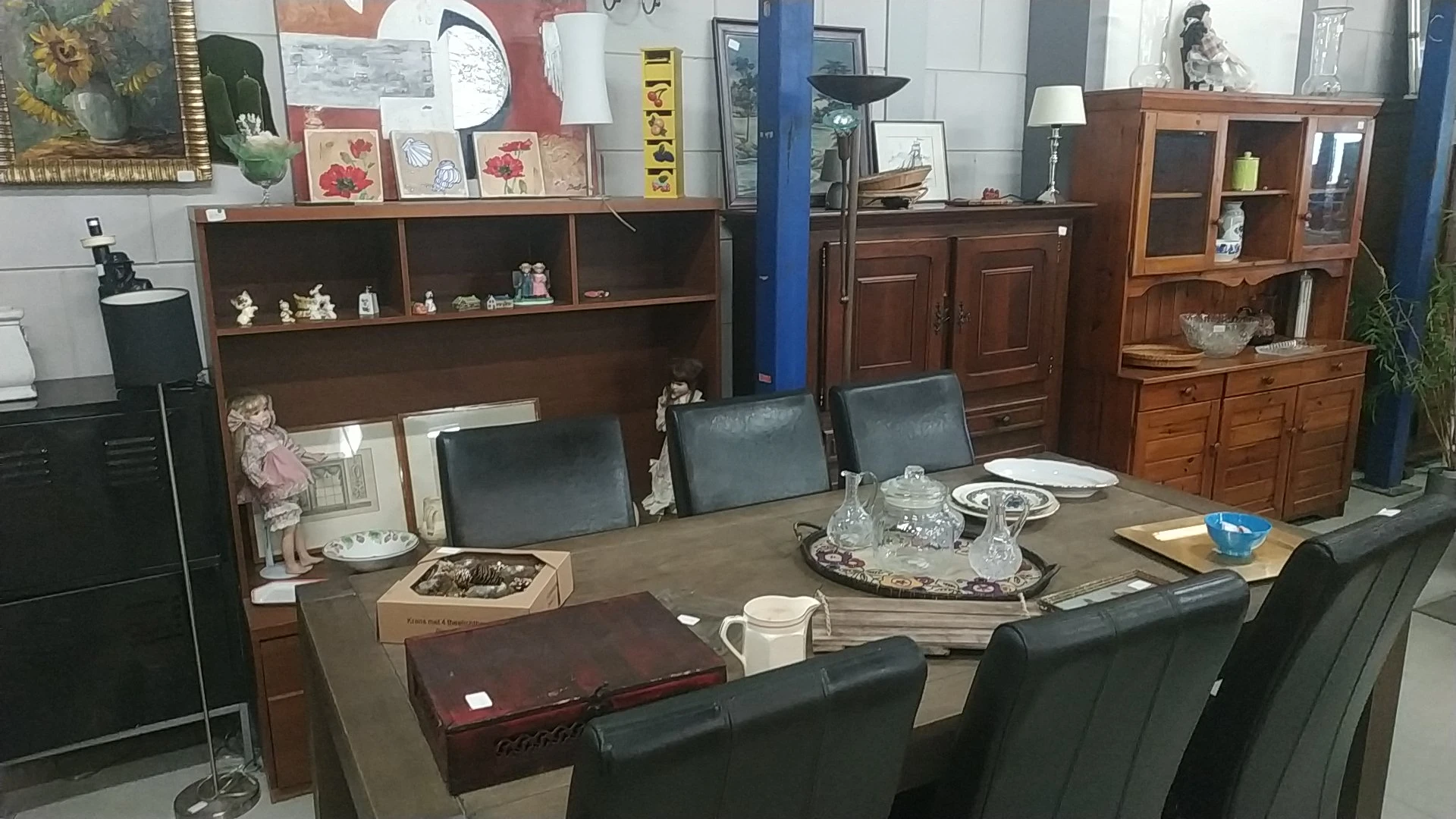 Winkelinterieur met houten meubels, vitrinekast, eettafel met stoelen en diverse huishoudelijke spullen op display