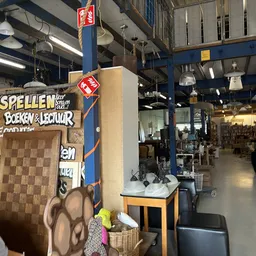 Winkelvloer met stellingen, displays en diverse tweedehands spullen onder industriële verlichting