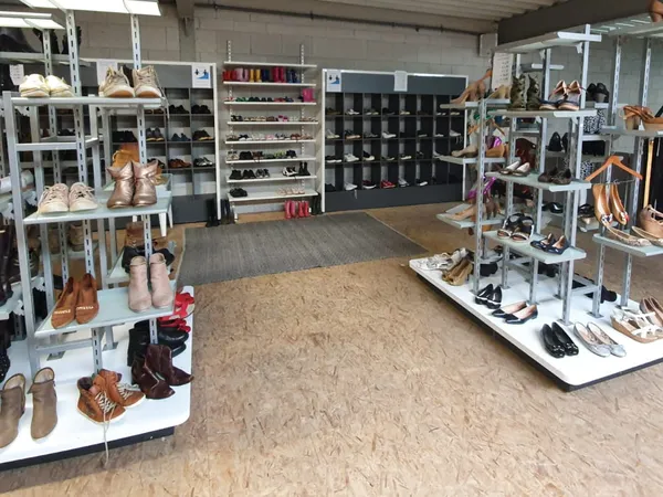 Winkelvloer met schoenenstallingen en rekken met tweedehands schoenen en accessoires in verschillende kleuren