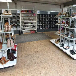 Winkelvloer met schoenenstallingen en rekken met tweedehands schoenen en accessoires in verschillende kleuren
