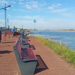 Bankjes langs een waterkanaal met uitzicht op water en groen