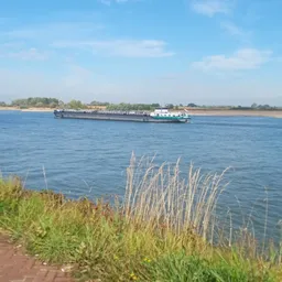 Vrachtschip op een rivier met groen land aan de oever