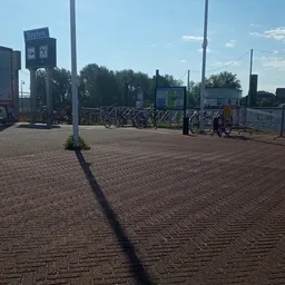Parkeerterrein met fietsenstalling en ingang van kringloopwinkel