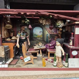 Miniatuurdiorama in rode houten kast met poppenhuis-scène en vintage accessoires